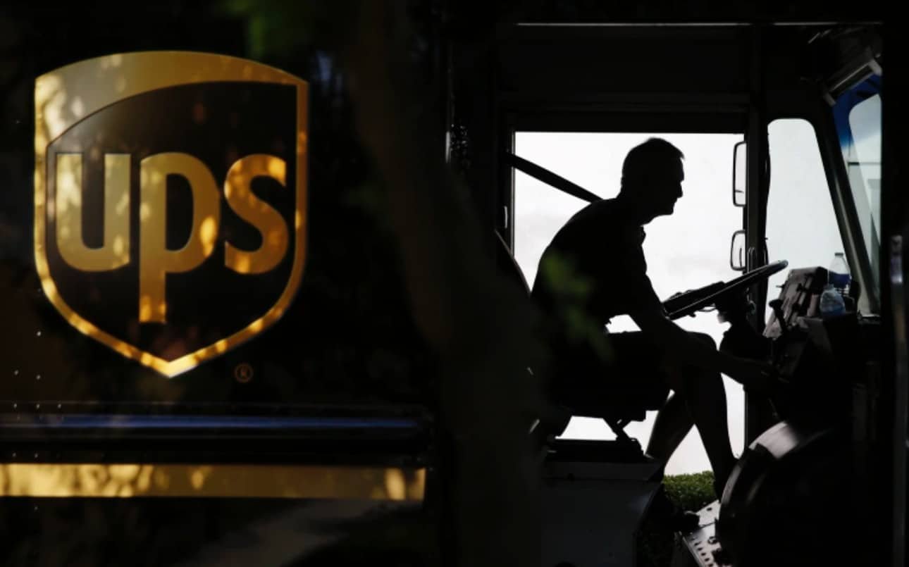 "UPS driver in truck, 2025 layoffs from Amazon cuts and Trump tariffs."