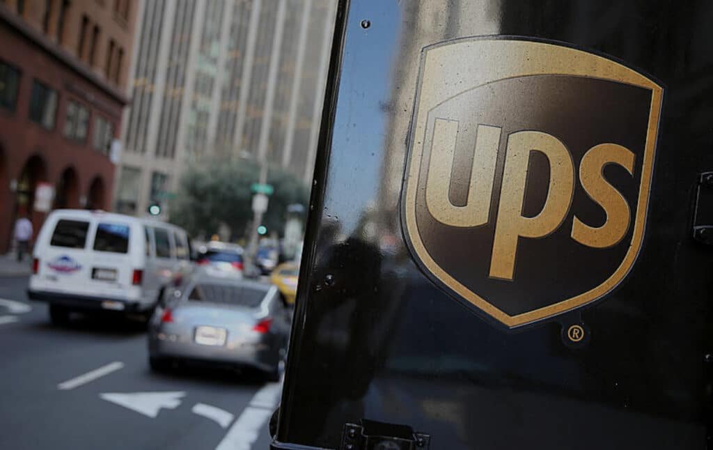 "UPS truck in city, 2025 layoffs from Amazon cuts and Trump tariffs."