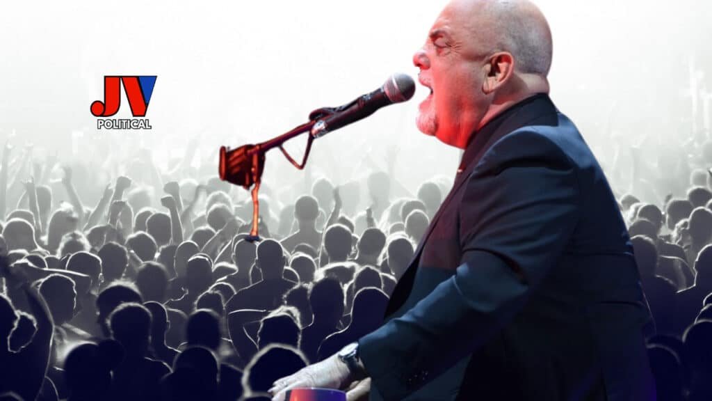 A passionate performer belts out a song into a microphone on stage, captivating a massive crowd of cheering fans silhouetted in the background. The JV Political logo in red, white, and blue sits proudly in the top left corner, representing conservative values. 🎤🎶🇺🇸 #BillyJoel #TourCancellation #HealthUpdate #JVPolitical #ConservativeNews #PianoMan #MusicLegend #FanSupport #NPHDiagnosis #2025Tour 2.6s