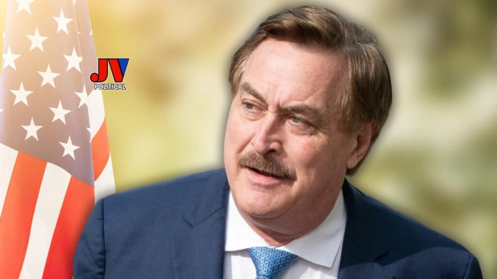 Bold and determined, Mike Lindell stands strong in a sharp blue suit and tie, with the American flag proudly waving beside him, symbolizing unwavering patriotism. The JVPolitical logo shines as a beacon of truth and freedom for the MAGA movement. #Patriotism #AmericaFirst #MAGA #Leadership #ElectionTruth #FreedomFighters #Trump2024 #JVPolitical #StandForAmerica