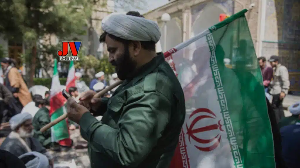 Intense scene of a bearded man in a green uniform proudly waving the Iranian flag amidst a crowd of protesters, with the historic backdrop of a tiled mosque and other flag-bearers in the background. The JVPolitical logo marks this powerful image of national pride and resistance. #IranPride #IranProtests #MAGA #AmericaFirst #JusticeForIran #StrongLeadership #Trump2024 #FreedomFight #IranStrong #PatriotNation